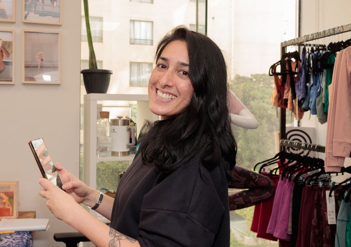 Smiling woman using smartphone in a vibrant clothing store setting.